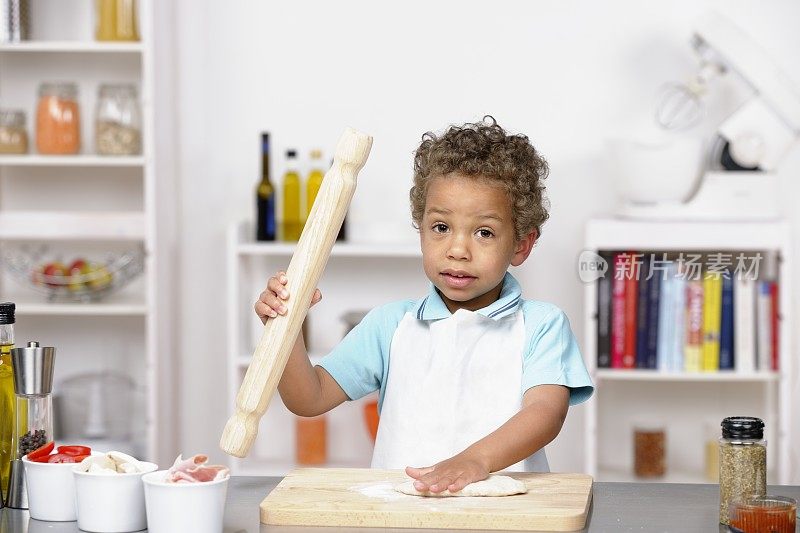 小男孩/幼童在准备披萨时拿着擀面杖